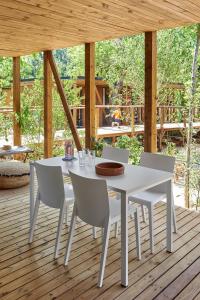 una mesa blanca y sillas en una terraza de madera en Rives d'Arc en Vallon-Pont-dʼArc