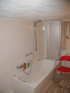 a bath tub in a bathroom with a red chair at Haus an der Radau in Bad Harzburg