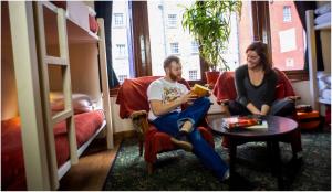 un hombre y una mujer leyendo un libro en una habitación con literas en Royal Mile Backpackers, en Edimburgo