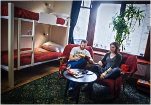 a man and woman sitting on chairs in a room with a bunk bed at Royal Mile Backpackers in Edinburgh