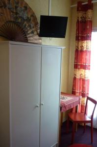 a white cabinet with a flat screen tv on top at Hôtel du Centre in Lourdes