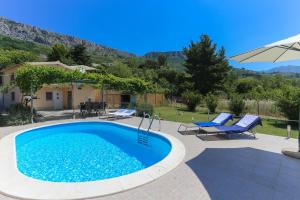 een zwembad met 2 stoelen en een parasol bij Holiday Home Rupotina with a large yard, pool and a beautiful view in Solin