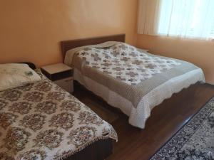 - une chambre avec 2 lits, une table de chevet et une fenêtre dans l'établissement Boomerang Guest house, à Cholpon-Ata