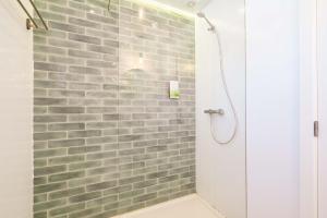 a bathroom with a shower with a brick wall at Wavesensations - Sagres Surf House in Sagres
