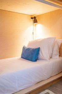 a white bed with a blue pillow on it at Wavesensations - Sagres Surf House in Sagres