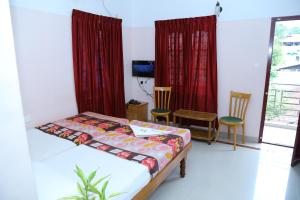 a bedroom with a bed and two chairs and a television at princess inn royal in Trivandrum