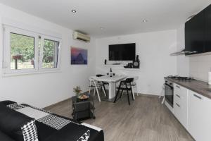 a white living room with a kitchen and a table at Holiday Home Rupotina with a large yard, pool and a beautiful view in Solin