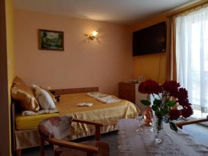 a bedroom with a bed and a table with flowers on it at Willa ANNA in Pustkowo