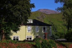 a yellow house with a mountain in the background at The Shielings by Inverlochy Villas in Fort William