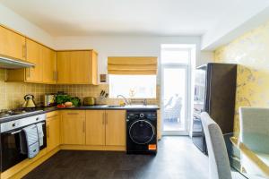 a kitchen with wooden cabinets and a washer and dryer at Hallam Lodge in Nelson