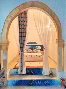 a bedroom with an archway with a bed with curtains at Dar Tenast in Houmt Souk