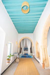 a room with a blue ceiling with a clock on it at Dar Tenast in Houmt Souk