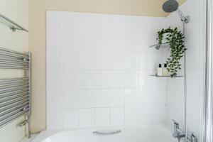 a white tiled bathroom with a tub and a plant at Hallam Lodge in Nelson +22 photos
