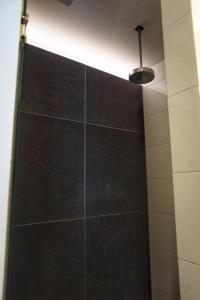 a shower with a black tile wall and a light at Bed & Wellness Boxtel, luxe kamer met airco en eigen badkamer in Boxtel
