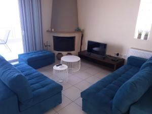 uma sala de estar com dois sofás azuis e uma televisão em Vrachati Sea Front House em Káto Ássos