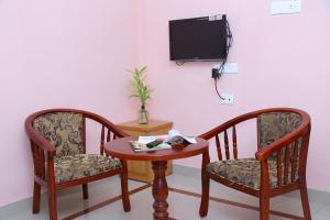 Habitación con 2 sillas, mesa y TV. en princess inn royal, en Trivandrum