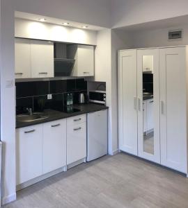 a white kitchen with white cabinets and a sink at Aparthotel 11 in Kwidzyn