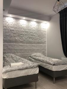 2 letti in una camera con muro di mattoni di Aparthotel 11 a Kwidzyn