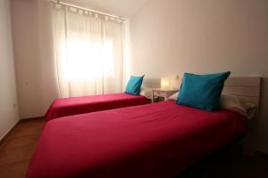 twee bedden in een kamer met rode lakens en blauwe kussens bij El Arrecorzo by #cherrygredos in El Arenal +20 foto's