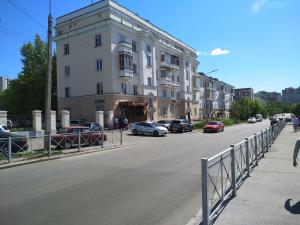 un edificio con coches aparcados al lado de una calle en Apartment Pavlyukhina 100 en Kazán