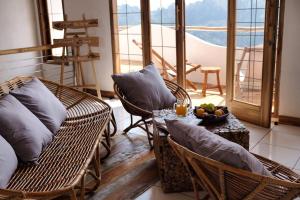 a room with wicker chairs and a table with a bowl of fruit at Boscha Villas 101 in Bandung