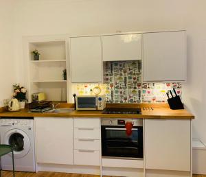 a kitchen with white cabinets and a microwave at 21 Melbourne Place Studios in St. Andrews