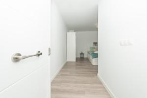 an open door to a hallway with white walls and wood floors at Fantásticos Lofts Malagueta in Málaga