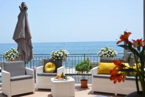 un grupo de sillas en un balcón con vistas al océano en ZI DIMA APARTMENTS, en Giardini Naxos