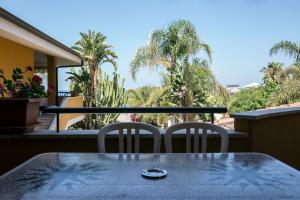 a table and chairs on a balcony with palm trees at Villaggio Tramonto in Capo Vaticano
