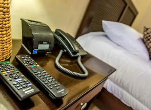 a phone and two remote controls on a table next to a bed at Palo Santo Galápagos Hotel in Puerto Ayora