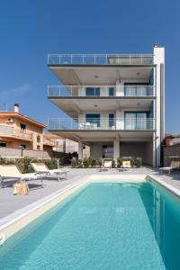 a building with a swimming pool in front of a building at Terraces d'Orlando - Family Apartments with Sea View and Pool in Capo dʼOrlando