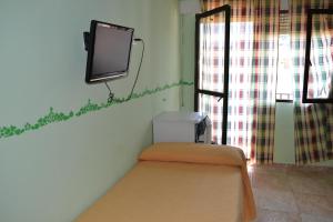 um quarto com uma televisão numa parede com um banco em Hostal Vadillo em Losar de la Vera