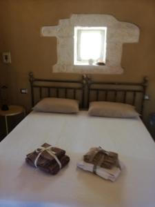 zwei Handtücher auf einem Bett mit Fenster in der Unterkunft Trullo Nonna Mari in Cisternino