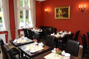 a restaurant with tables and chairs in a room with red walls at Hotel zum Hofmaler in Potsdam