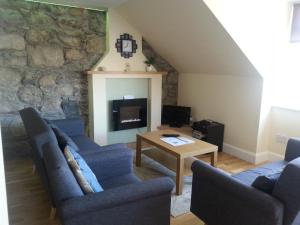 ein Wohnzimmer mit blauen Stühlen, einem Tisch und einer Steinmauer in der Unterkunft Combie Home in Oban
