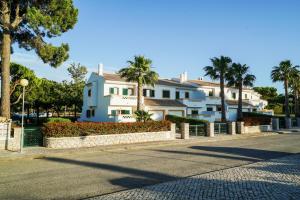 a large white building with palm trees and a street at Falésia Beach Villa by The Portuguese Butler in Olhos de Água