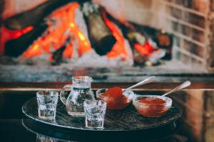 ein Tablett mit Tassen und Gläsern auf einem Tisch vor einem Feuer in der Unterkunft Etheres Tzoumerkon Mountain Resort in Katarráktis