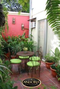 un patio con mesa, sillas y una pared roja en Hotel Andoria en San Salvador
