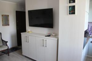 um armário branco com uma televisão de ecrã plano na parede em Apartament Nadmorski Zalewowa 12G em Sztutowo