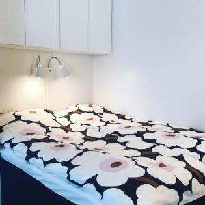 a bed with a black and white blanket with flowers at PikkuParlamentti in Pori
