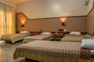 a hotel room with three beds in a room at Hotel Rio Grande in Cachoeiro de Itapemirim