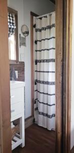 La salle de bains est pourvue d'un rideau de douche noir et blanc. dans l'établissement The Harmony Oaks Homestead, à Masaryktown