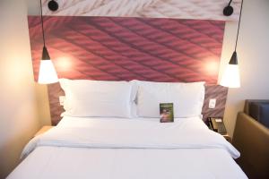 a bedroom with a white bed with a red headboard at Hotel Ibis Tatui in Tatuí