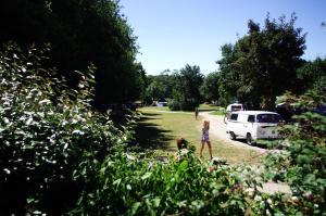 une fille marchant dans un champ avec une camionnette blanche dans l'établissement Camping La Bergerie, à La Chapelle-Achard