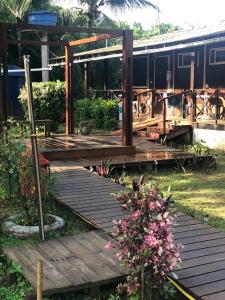 una terraza de madera en un jardín con un tren de fondo en Pousada Boldró Home, en Fernando de Noronha