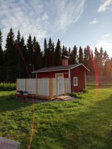 a small red cabin in a field with trees at Suomela Camping in Kärsämäki +23 photos