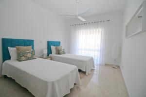 a white room with two beds and a window at Casa da Cidade in Lagos