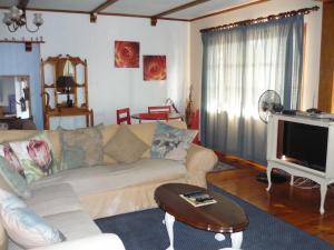 ein Wohnzimmer mit einem Sofa und einem TV in der Unterkunft A1Bay View Collection Cottage, Apartment solar power in Jeffreys Bay