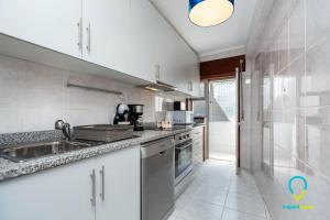 eine Küche mit weißen Schränken und einem Waschbecken in der Unterkunft Camilo Apartment in Porto