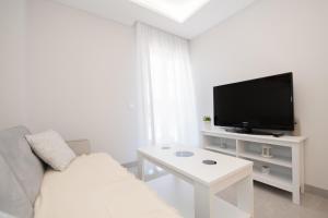 uma sala de estar branca com um sofá branco e uma televisão em Cubo's Apartamento Tivoli B4 em Benalmádena